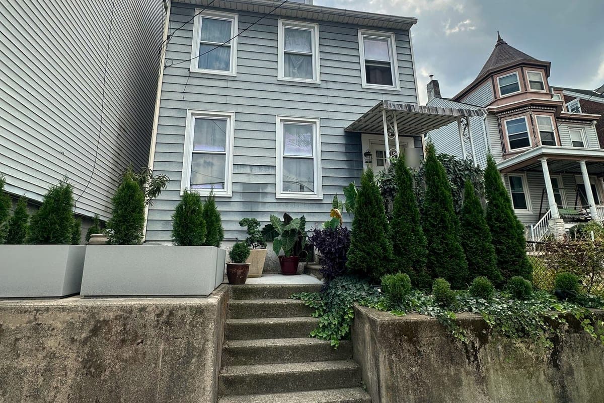A narrow grey house above stone steps and a retaining wall in Easton, bought by ClearEdge