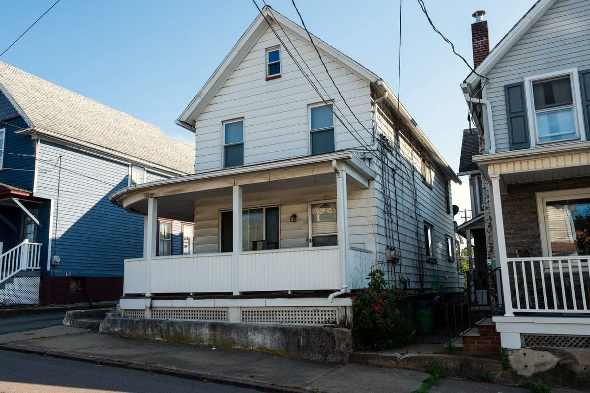 A white frame house with a deep front porch on a sloping street in Scranton, bought by ClearEdge