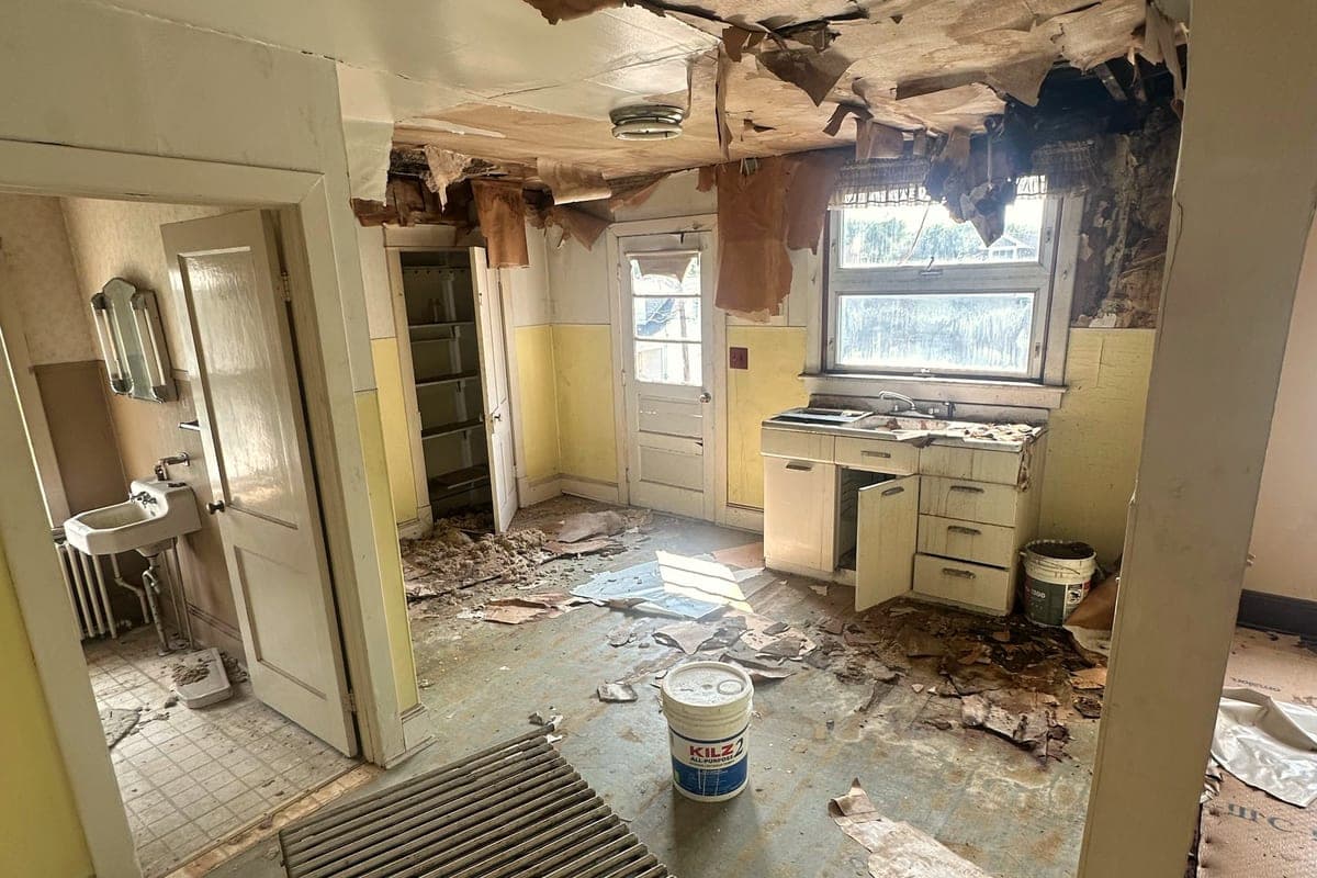 A kitchen with a collapsed ceiling and debris on the floor